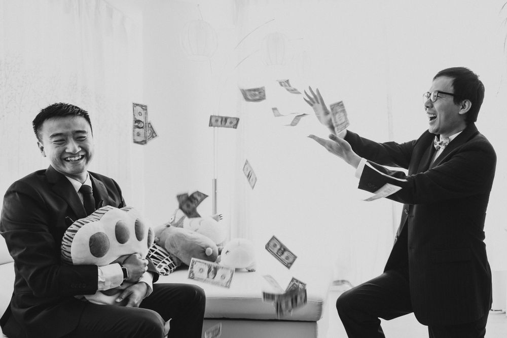 Two men in suits playfully throwing money in the air during a celebration.