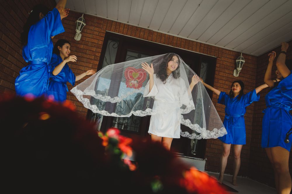 Wedding party scene with bride in white dress and bridesmaids in blue dresses dancing.