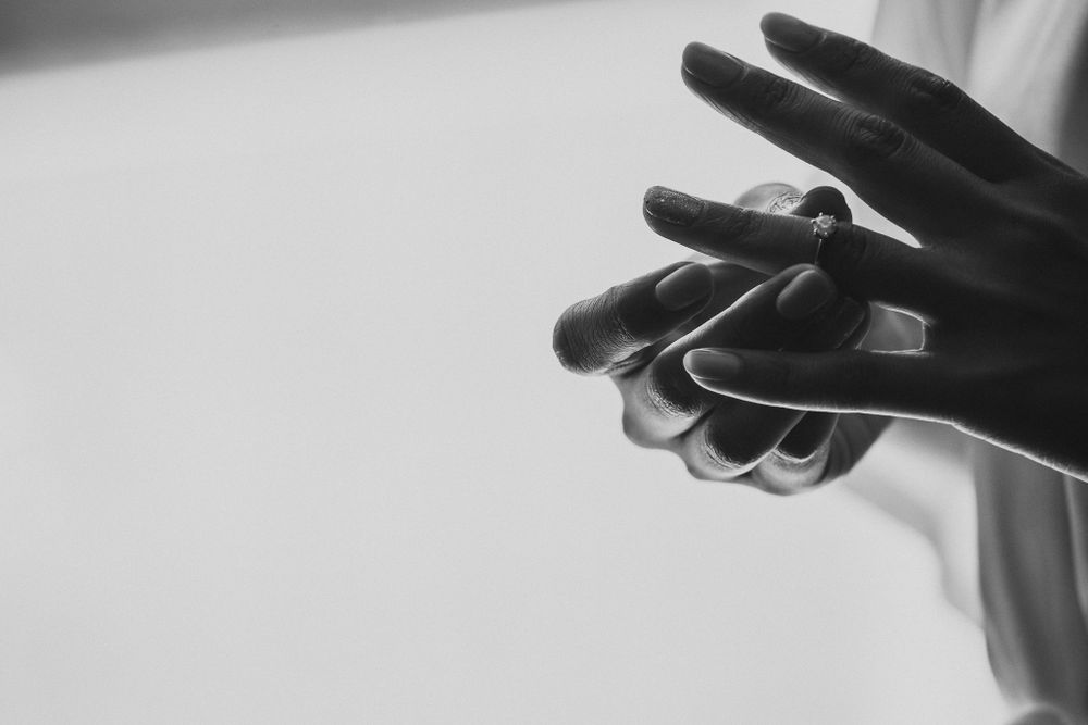 Artistic black and white close-up of hands with dramatic lighting and shadows.