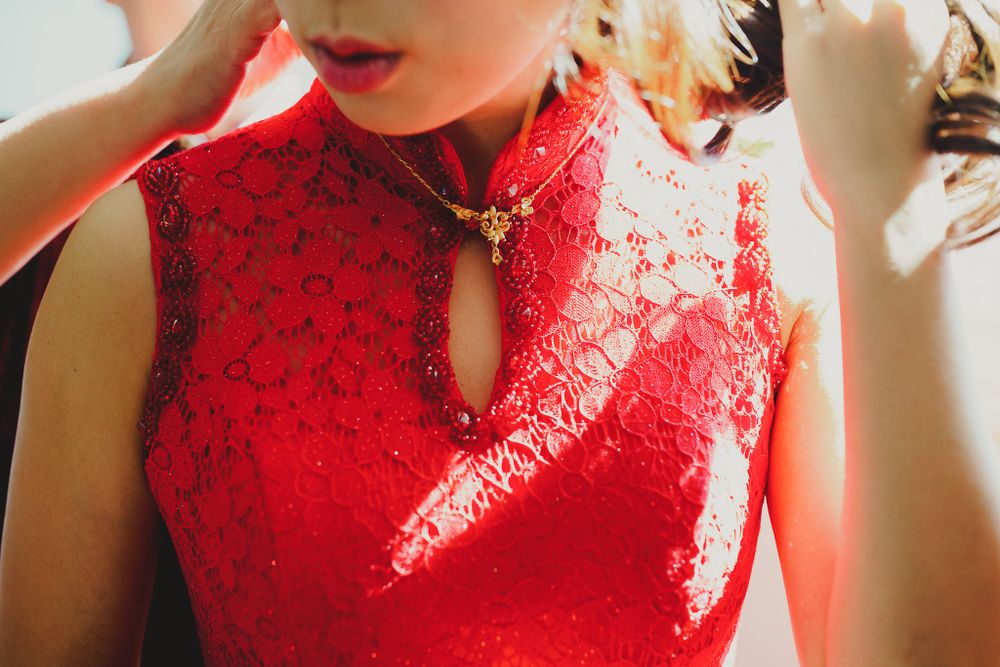 A close-up view of a red lace mandarin collar qipao dress with delicate traditional details.