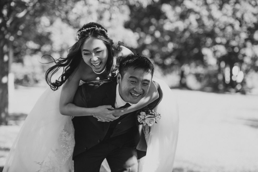 Joyful black and white photo of a piggyback ride in wedding attire.