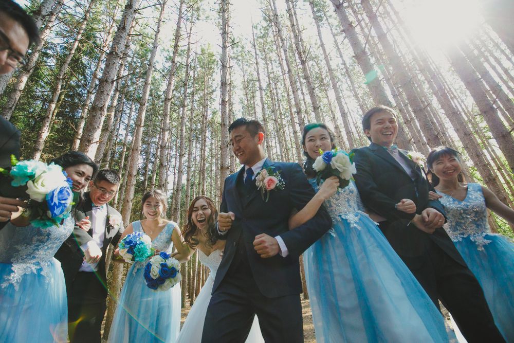 Wedding party posing in a forest with bridesmaids in blue dresses.