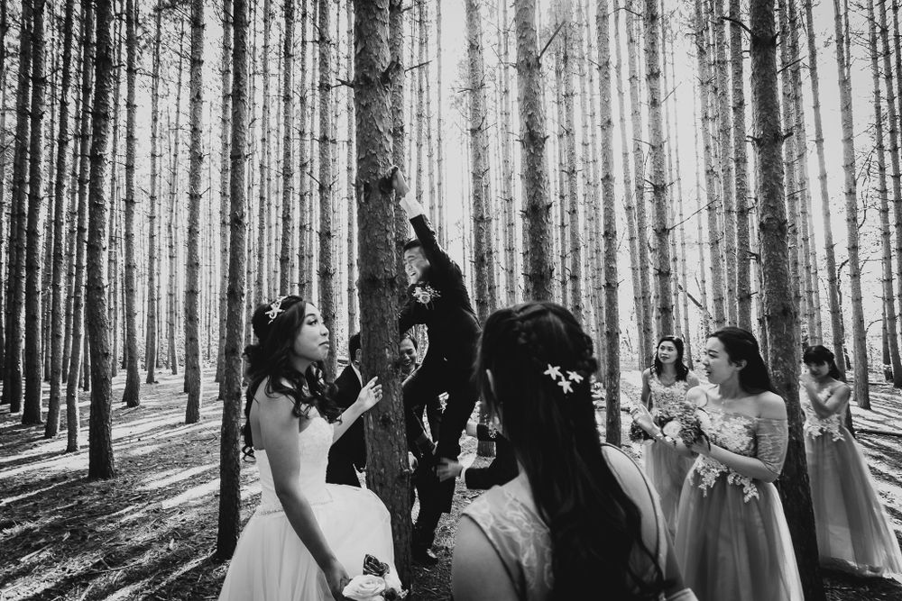 Black and white photo of a wedding party celebrating in a forest setting.