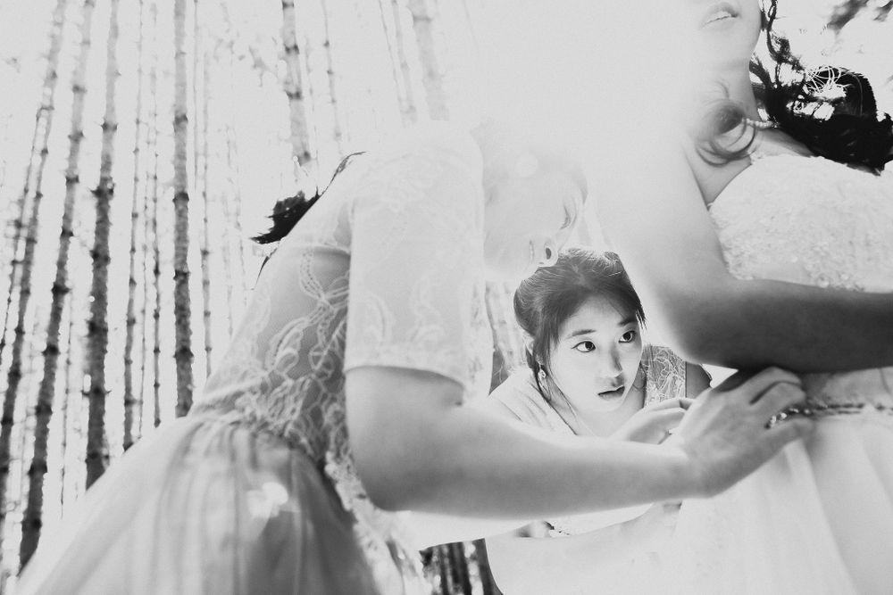 Black and white behind-the-scenes shot of wedding dress preparations.