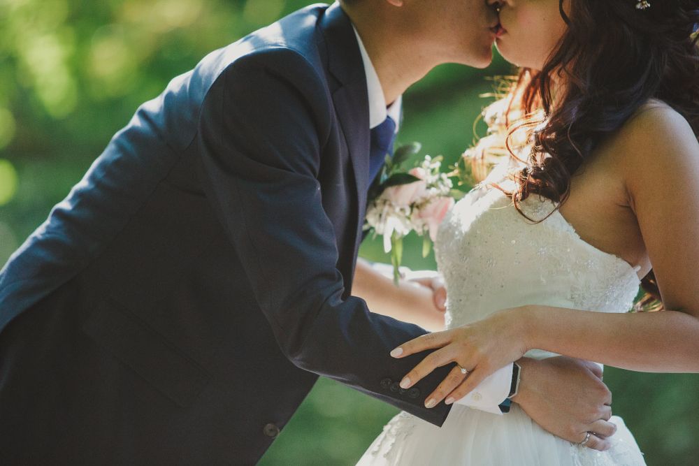 A tender embrace between newlyweds in a garden setting.