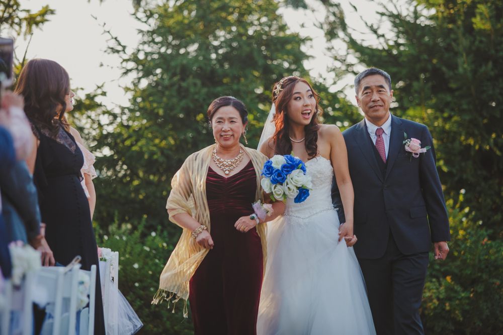 A wedding ceremony procession outdoors surrounded by trees and guests.