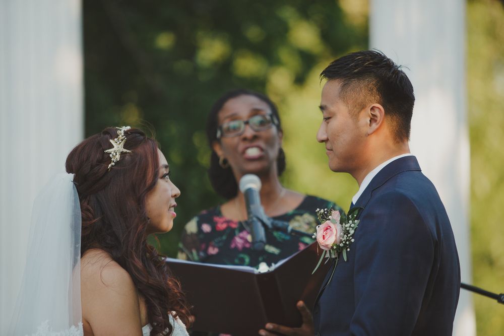 An intimate outdoor wedding ceremony taking place between white pillars.