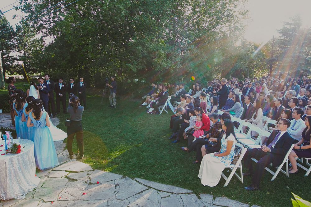 An aerial view of an outdoor wedding ceremony with guests seated on white chairs.