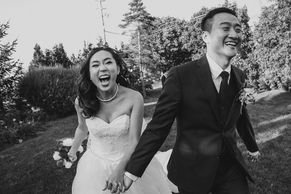 A joyful couple runs through a garden during their wedding celebration.