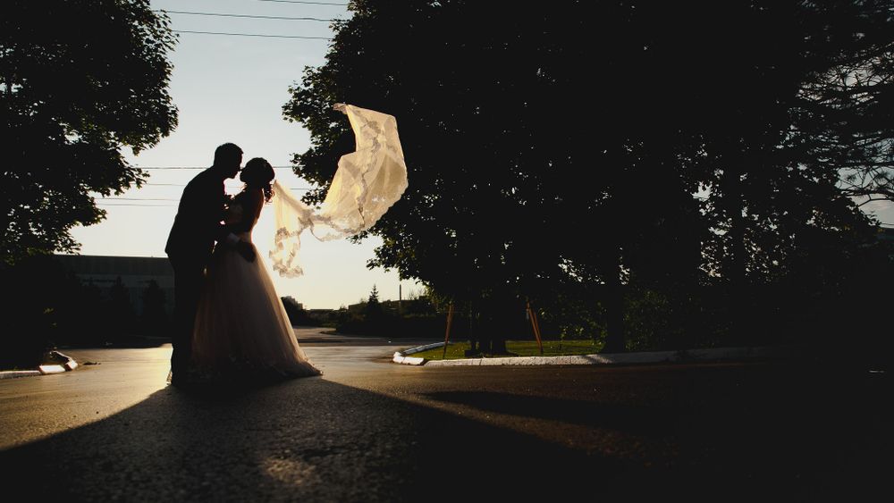 A silhouetted couple creates a dramatic wedding portrait at sunset.