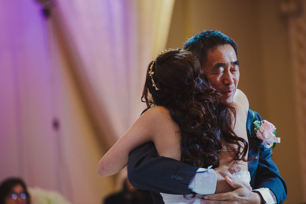 An emotional embrace during a wedding reception illuminated by warm ambient lighting.
