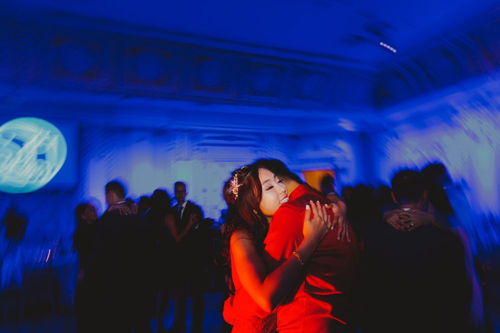 Couples dancing in a dimly lit reception venue with blue ambient lighting.