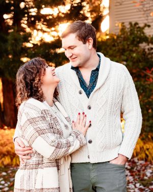 An engaged couple look lovingly at each other while the sun sets behind them