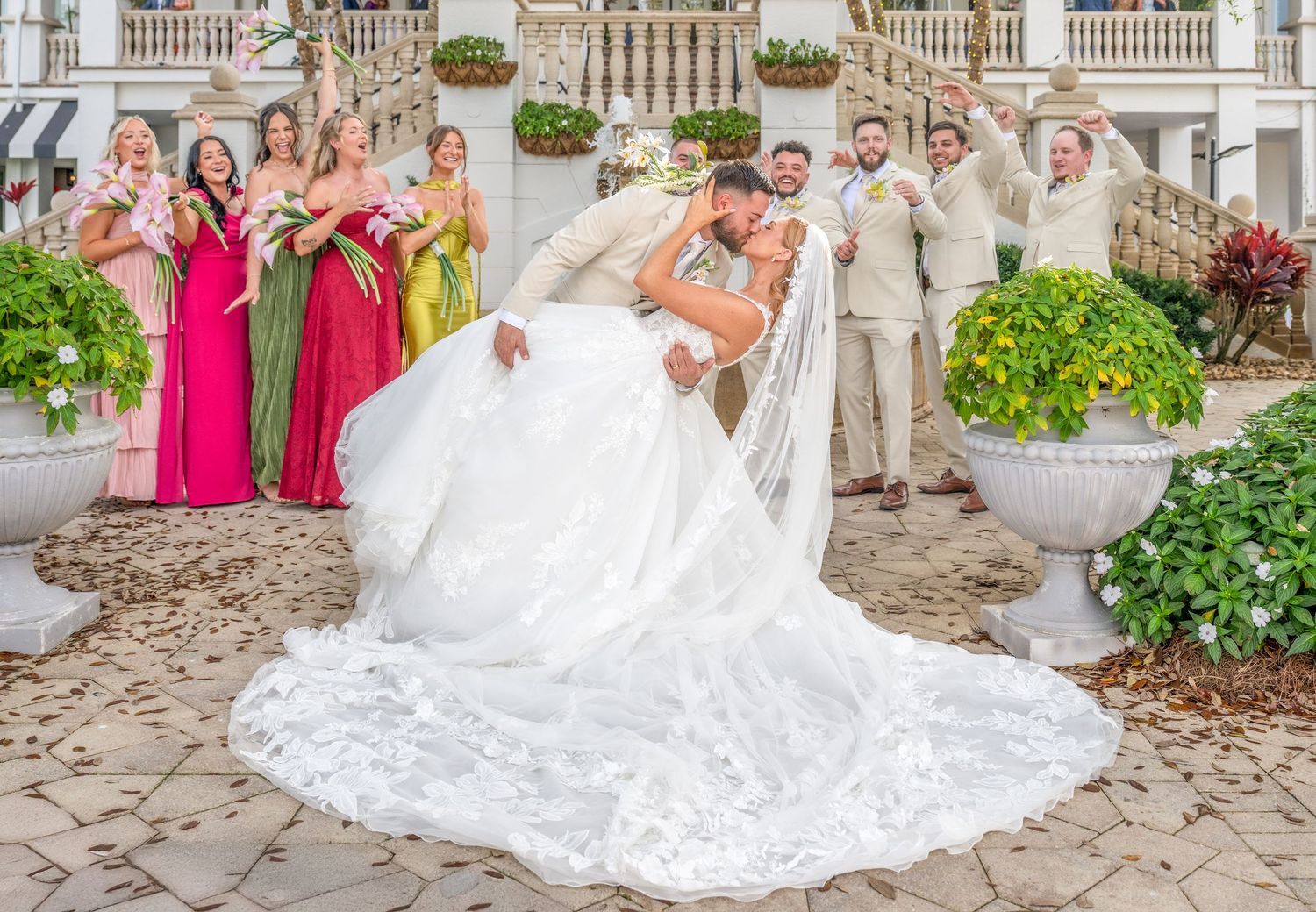 Newlywed couple shares an intimate moment under greenery at an outdoor wedding celebration.