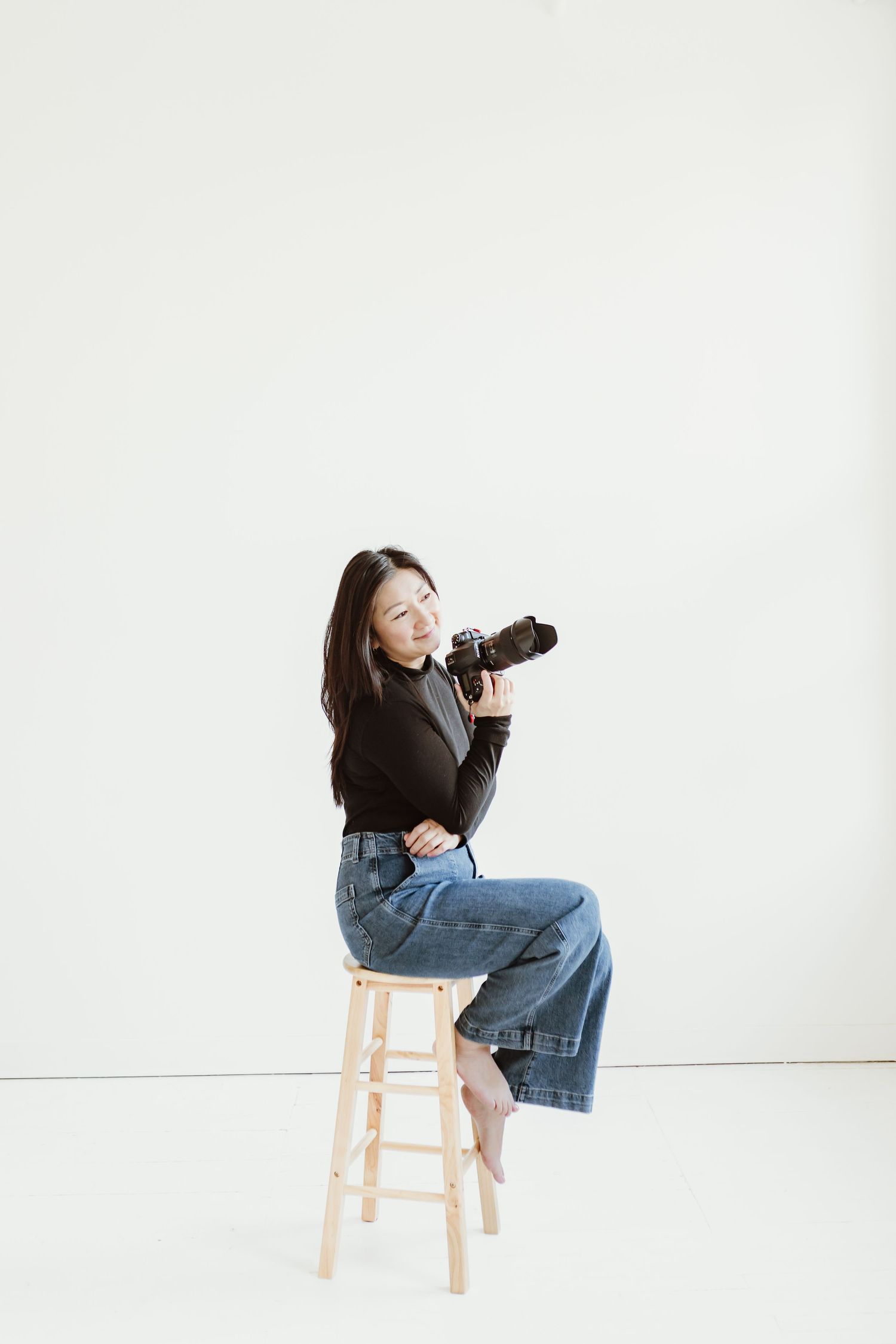 photographer sitting on a stool holding camera with right arm while looking out