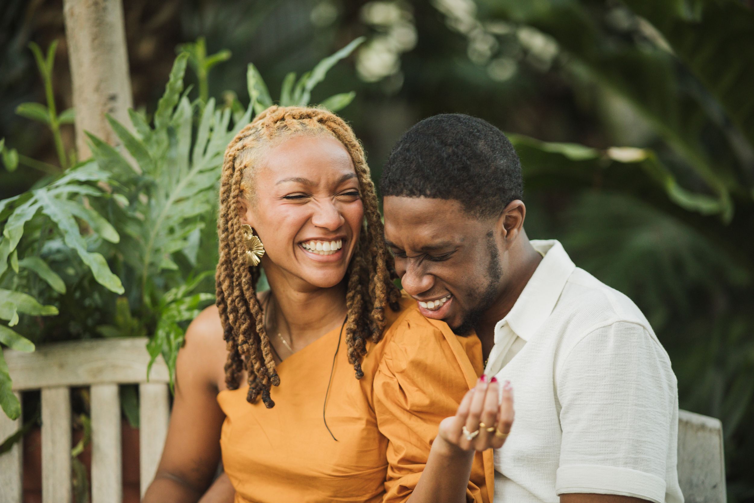 Joyful outdoor portrait of couple in matching earth tones sharing genuine laughter.