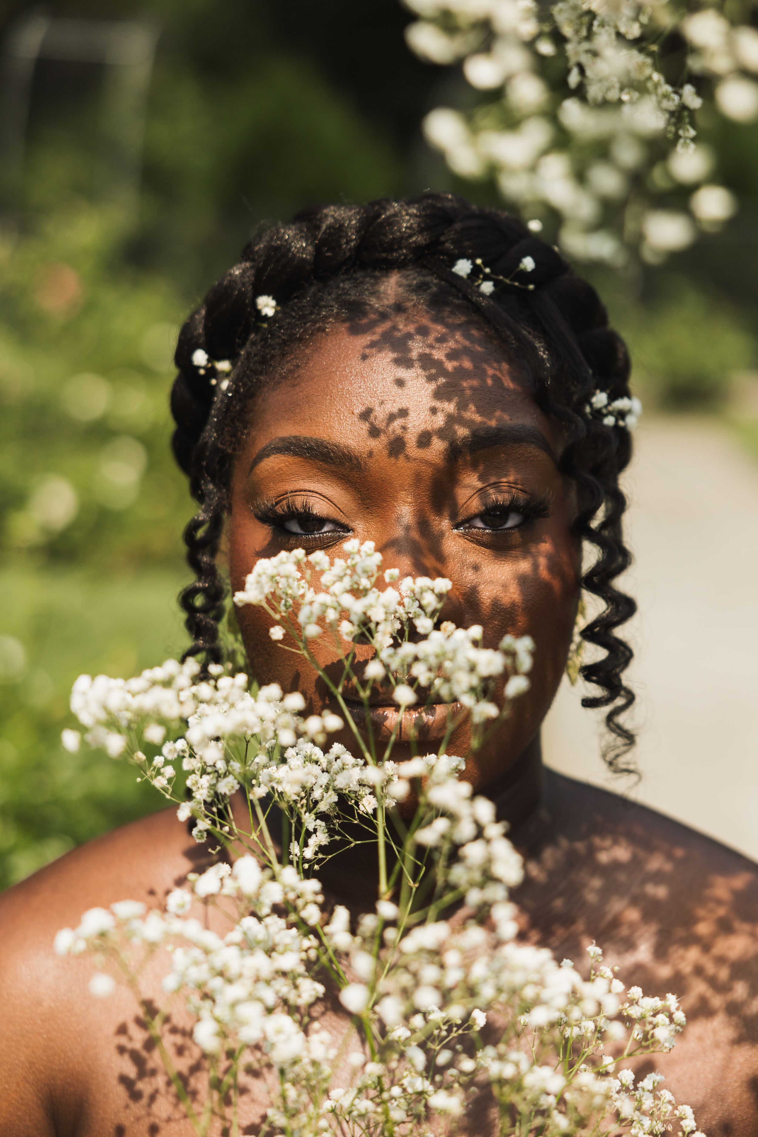 Close-up portrait with baby's breath flowers creating dreamy effect against natural bokeh background.