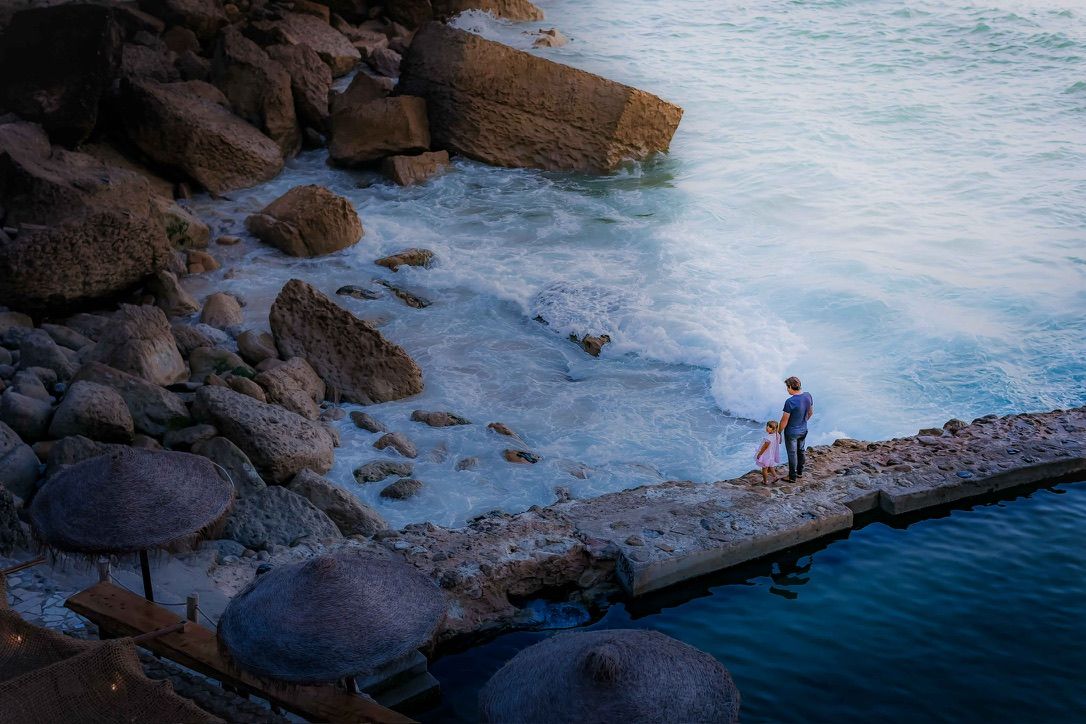 A scenic coastal landscape with rocky cliffs and blue ocean water stretching to the horizon.