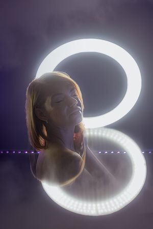 Glowing circular light trails create a mesmerizing spiral pattern against a purple background.