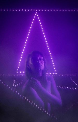 Purple LED lights form a triangular pattern in a moody atmospheric setting.