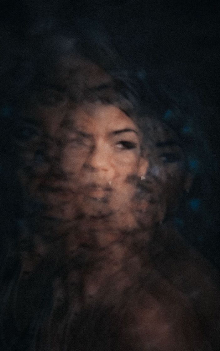 Dreamy double exposure effect creates a mysterious atmospheric portrait in darkness.