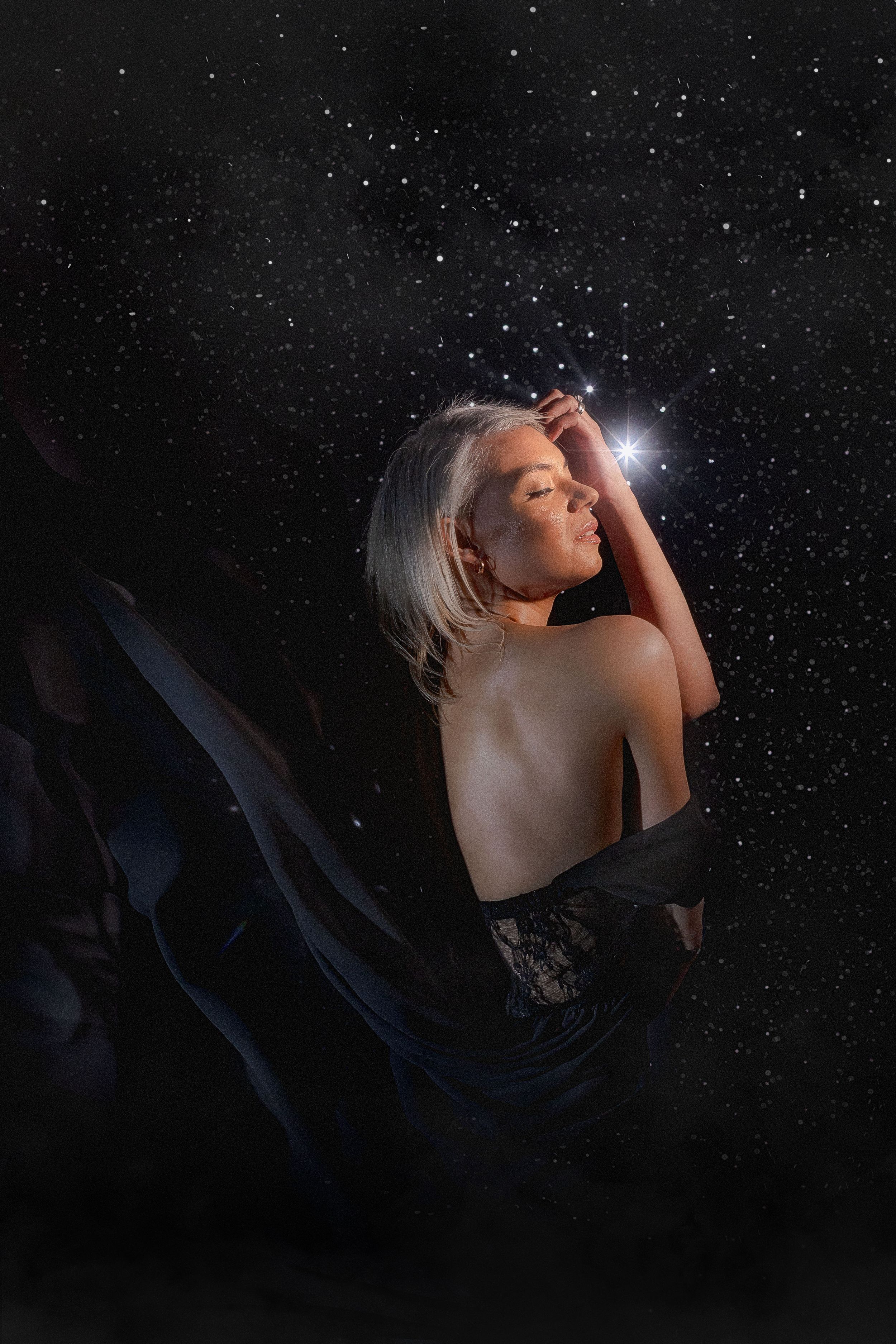 A silhouetted figure poses dramatically against a starry night sky background in an artistic portrait series.