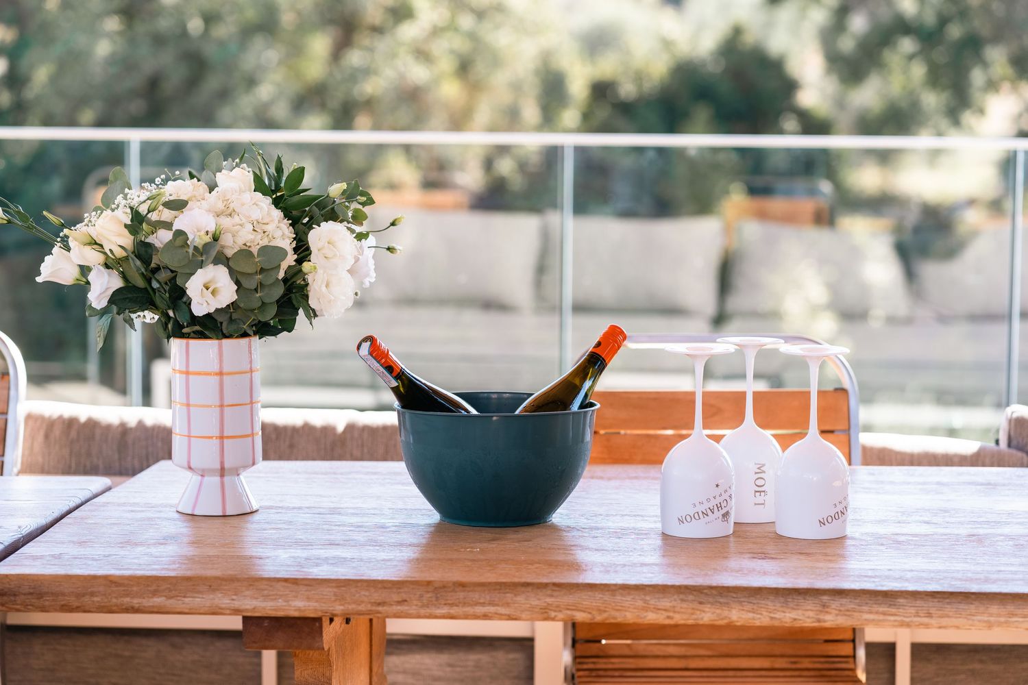 Elegant table setting with wine bottles chilling in ice bucket, wine glasses, and pink floral centerpiece.