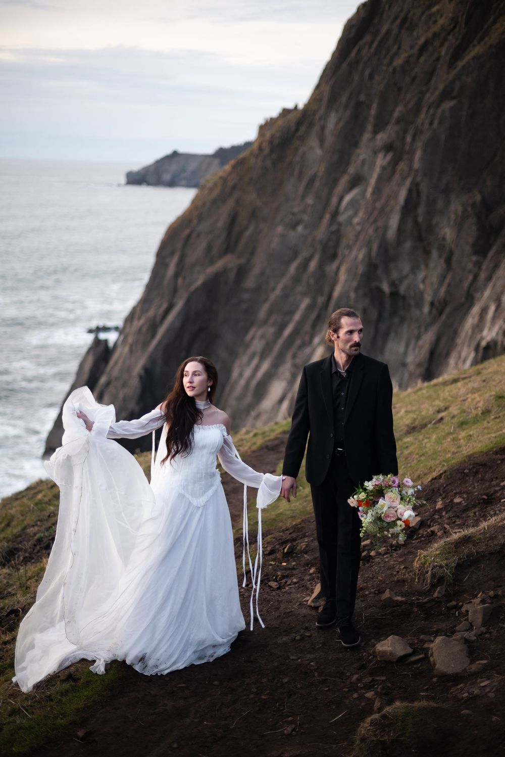 A dramatic wedding photo session on rocky coastal cliffs.