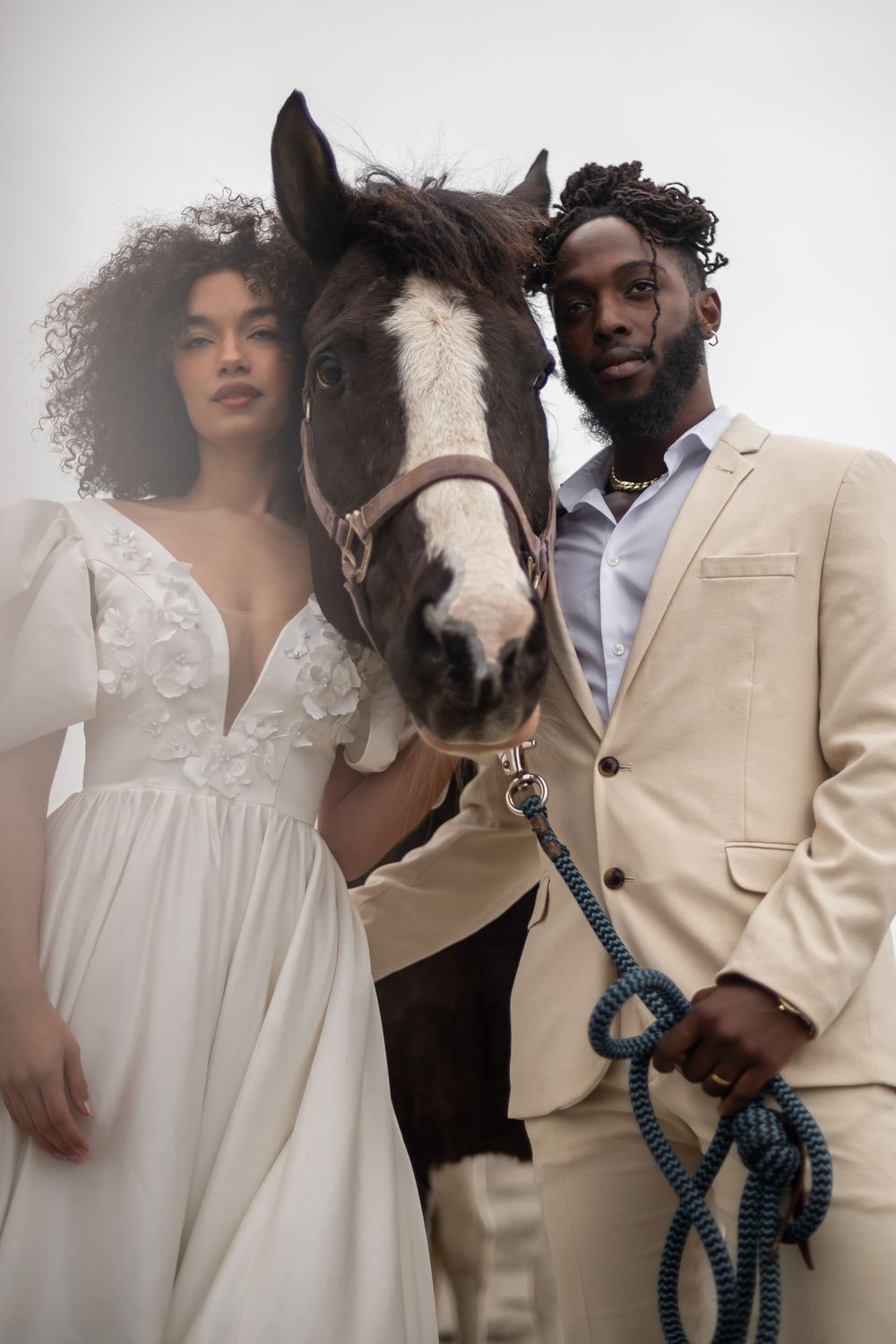 A wedding photoshoot featuring a couple and their miniature horse in white and cream attire.