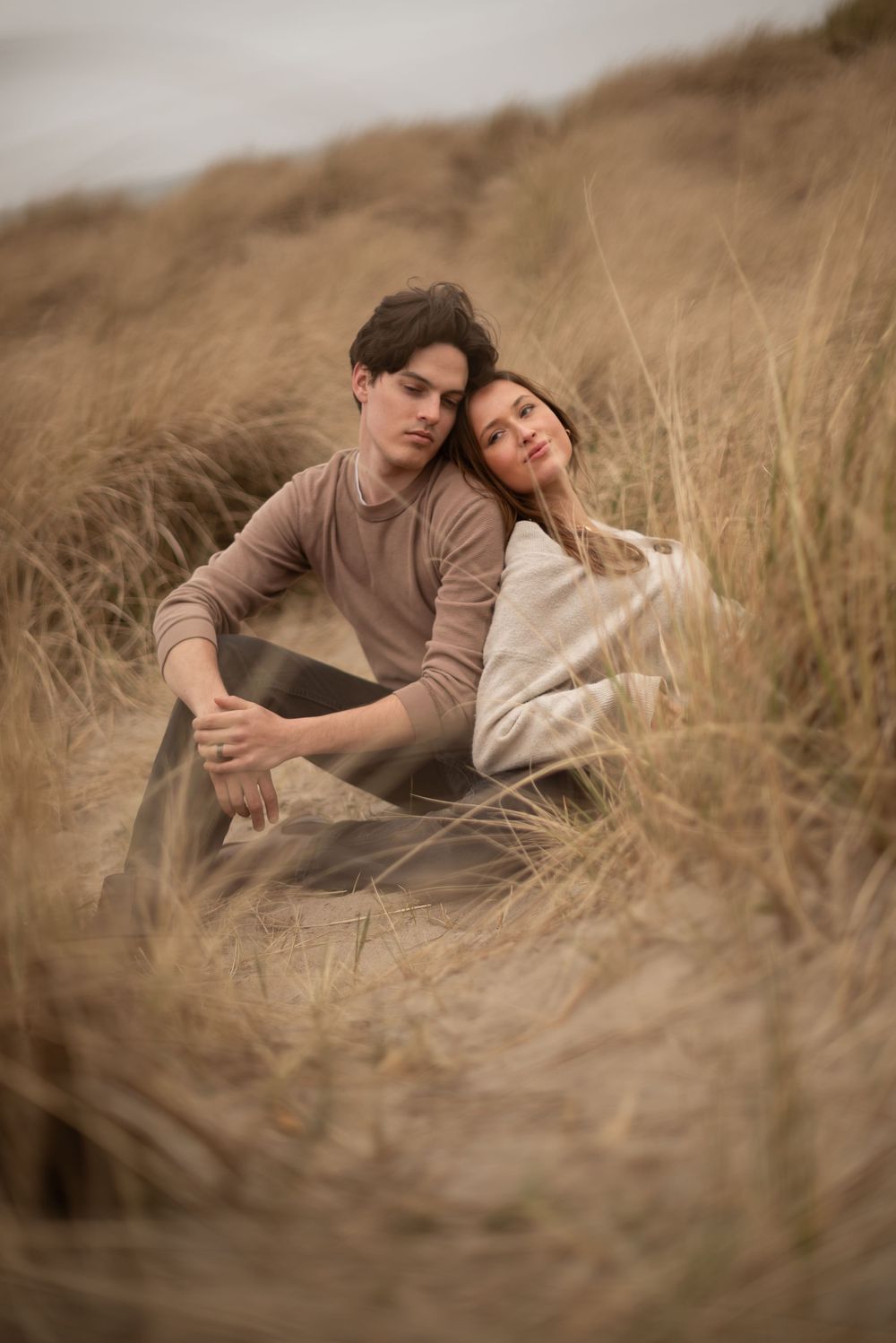 A romantic couple lying in golden grass during sunset.