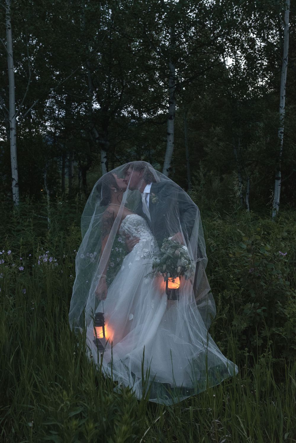Ethereal white fabric glows with candlelight in a misty forest setting at dusk.