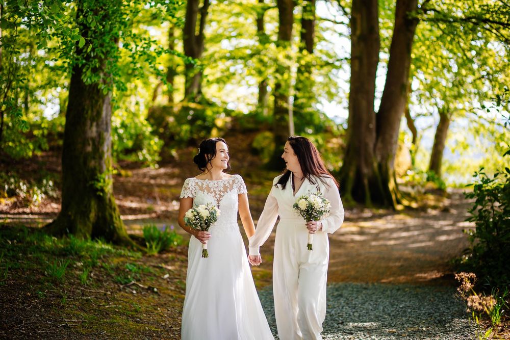 Two brides hold hands amongst the woodland at Storrs Hall. LGBTQ friendly Lancashire wedding photographer, Lynette Matthews Photography