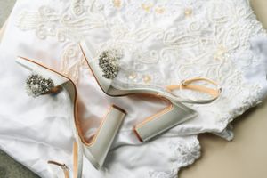 White lace wedding dress fabric with elegant silver heels and baby's breath floral accents.