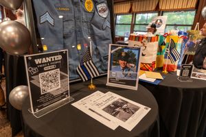 Police uniform display with wanted posters and black balloons at an event setup table.
