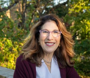 Professional portrait against autumn foliage background with wooden railing.