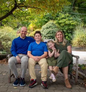 Family sitting together on a garden bench surrounded by lush greenery.