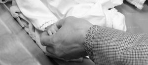 Close-up black and white image of hands during a baptism ceremony.