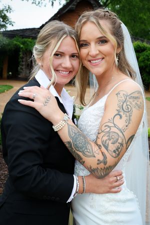 A bride with intricate arm tattoos shares intimate moments during wedding photos.
