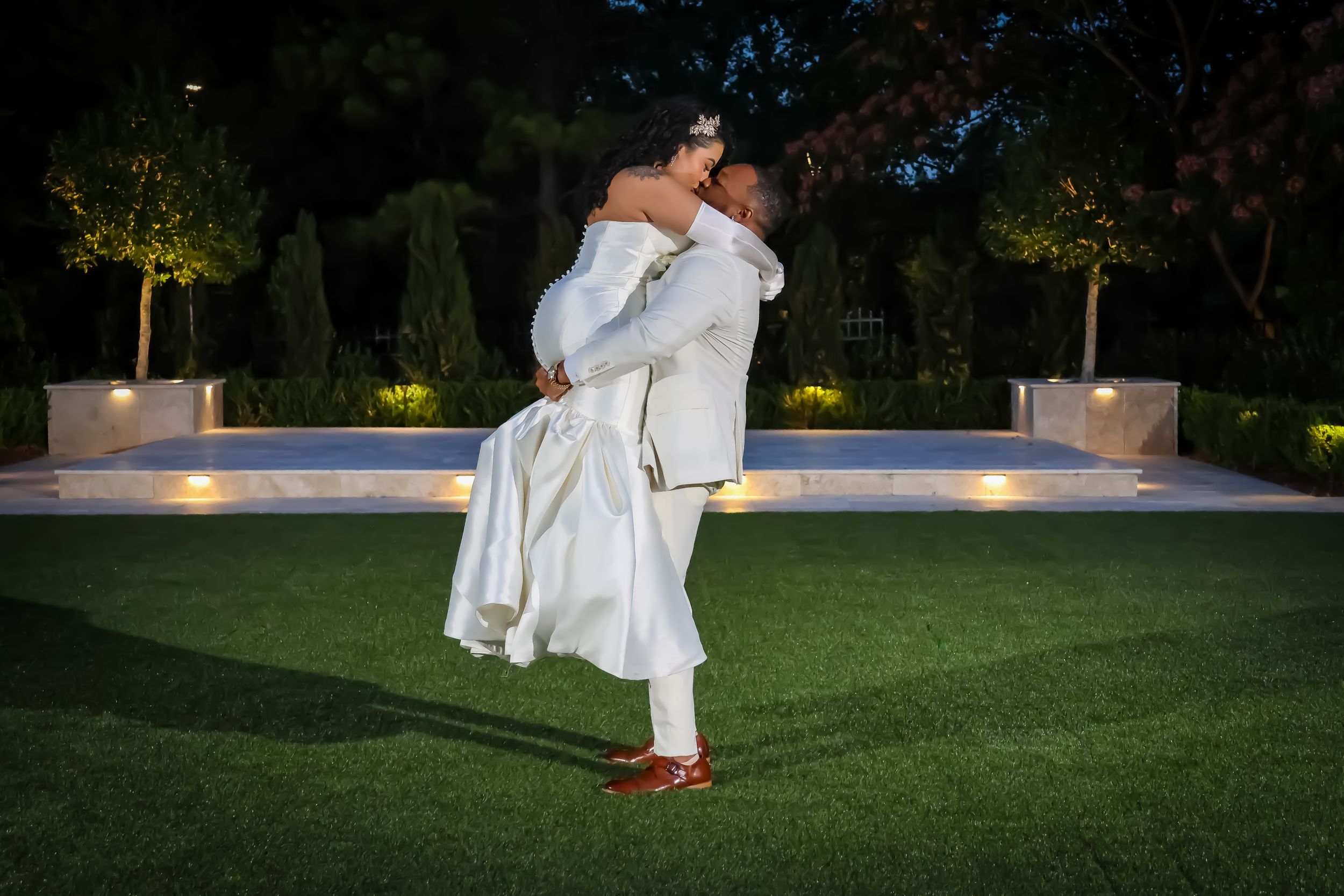 Evening wedding photography on manicured lawn with dramatic lighting.