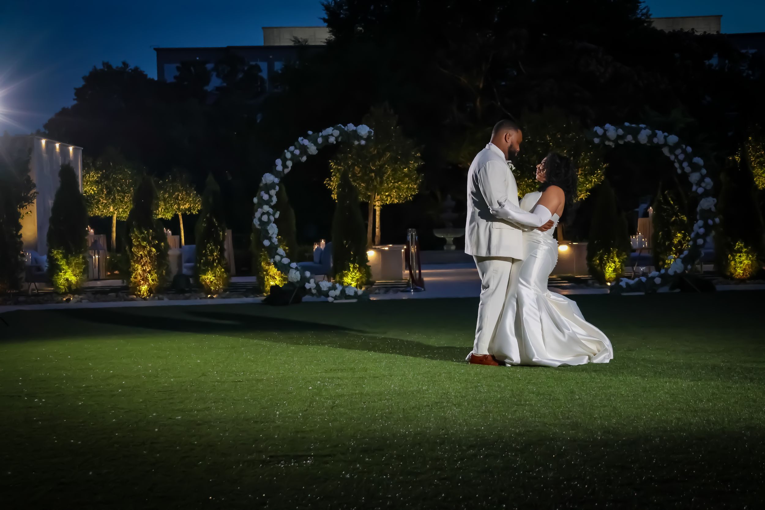 Romantic outdoor wedding photoshoot at sunset with string lights creating a magical atmosphere.