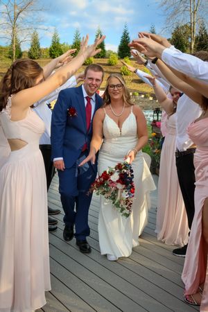 Wedding party celebrates on a wooden deck with bridesmaids in pink dresses.