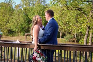 A romantic wedding photoshoot on a wooden deck surrounded by lush greenery.