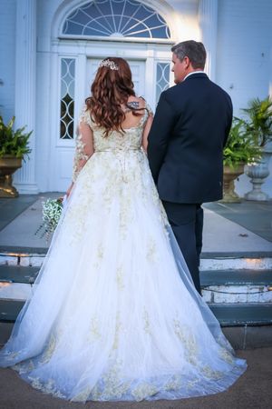 Dramatic wedding dress with long train photographed against white colonial architecture.