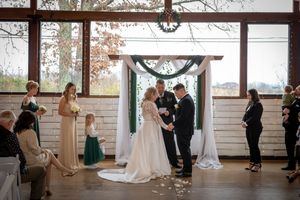 Wedding ceremony in progress inside rustic wooden venue with natural lighting.