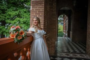 A wedding couple poses in a brick archway with elegant decor and floral arrangements.