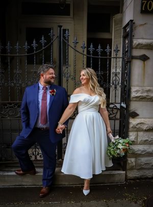 A couple shares intimate moments in front of an ornate iron gate and stone building.