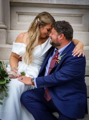 A tender moment between newlyweds sitting together on stone steps.