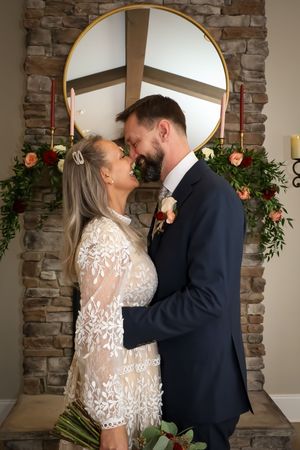 Romantic moment captured under stone archway with decorative mirrors and floral arrangements.