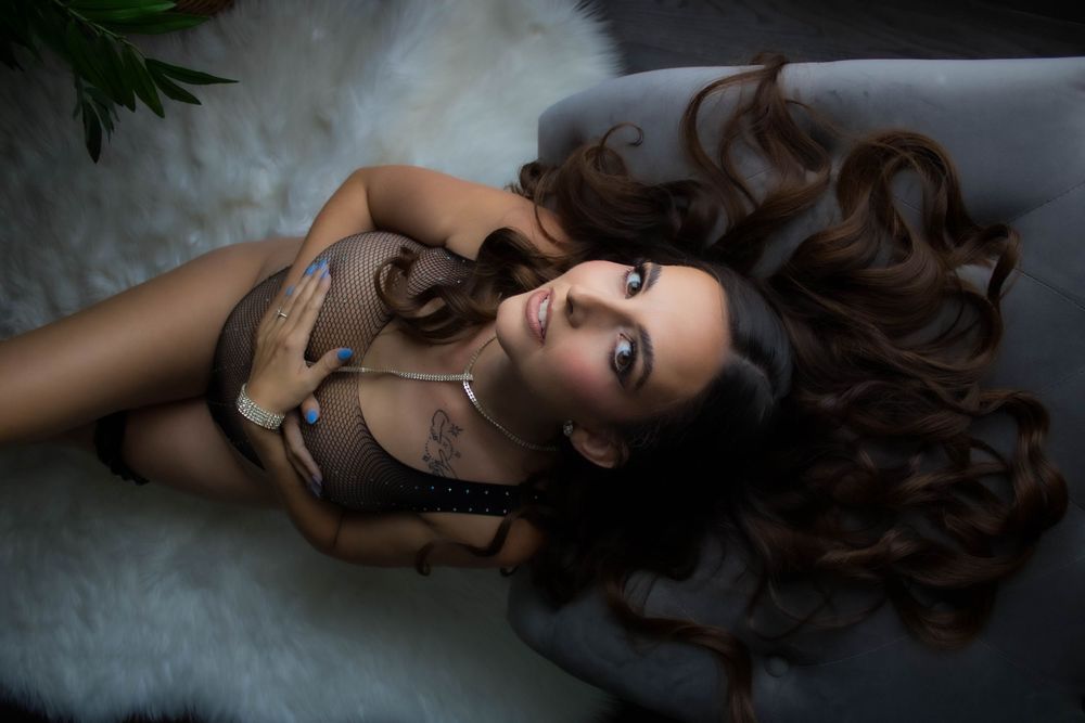 Artistic portrait series of a woman with long brown hair lying on grey fabric in dramatic lighting.