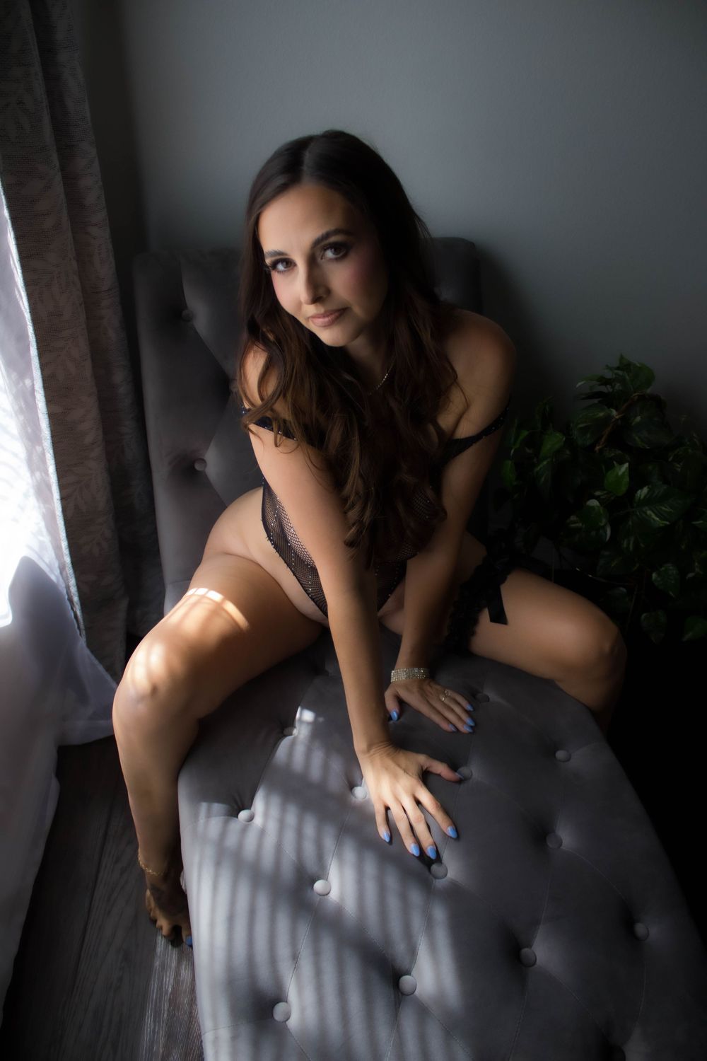 A series of moody boudoir photos showing someone in dark attire posing against dramatic window lighting.